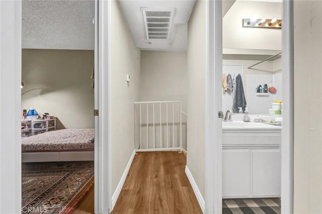 hall with hardwood / wood-style floors, sink, and a textured ceiling