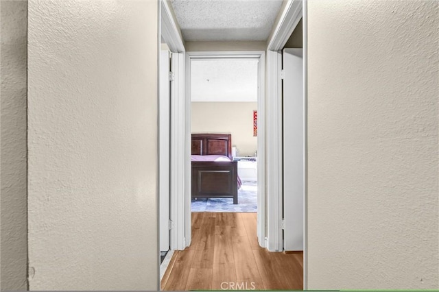 hallway featuring light hardwood / wood-style floors and a textured ceiling