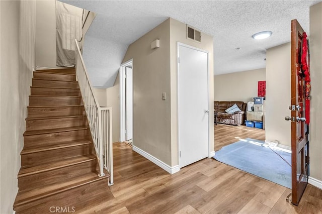 staircase featuring hardwood / wood-style floors and a textured ceiling