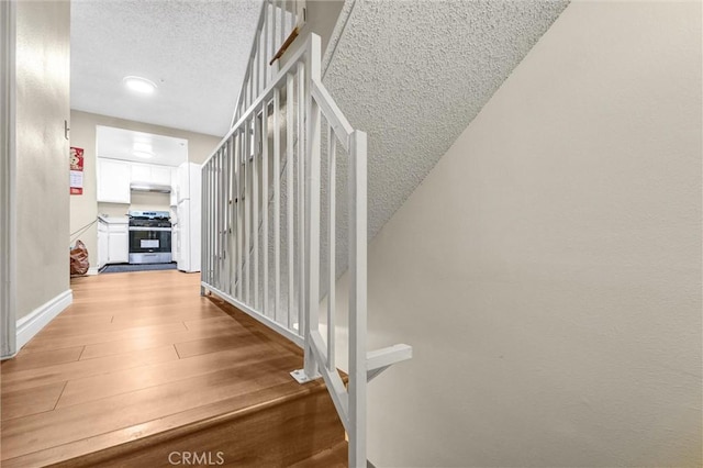 stairway with hardwood / wood-style flooring and a textured ceiling