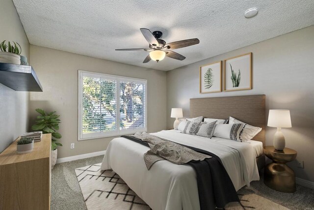 bedroom featuring ceiling fan, light colored carpet, and a textured ceiling