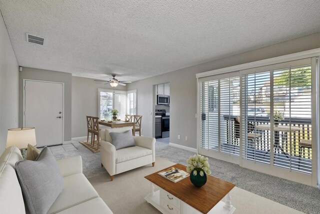 carpeted living room featuring ceiling fan, plenty of natural light, and a textured ceiling