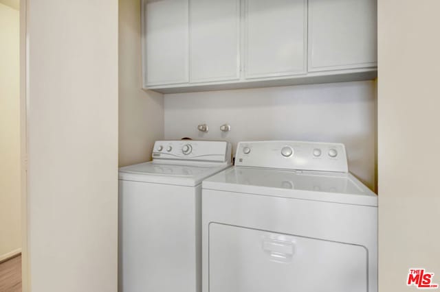 washroom with cabinets, light hardwood / wood-style flooring, and washer and clothes dryer