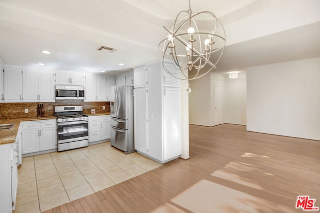 kitchen featuring pendant lighting, white cabinets, light hardwood / wood-style flooring, appliances with stainless steel finishes, and a chandelier