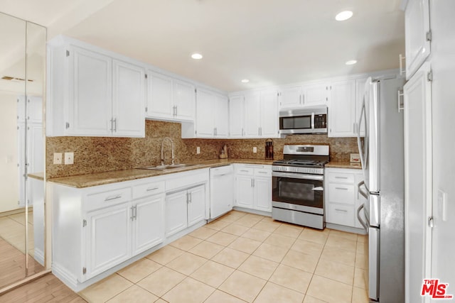 kitchen with light stone countertops, white cabinetry, sink, and stainless steel appliances