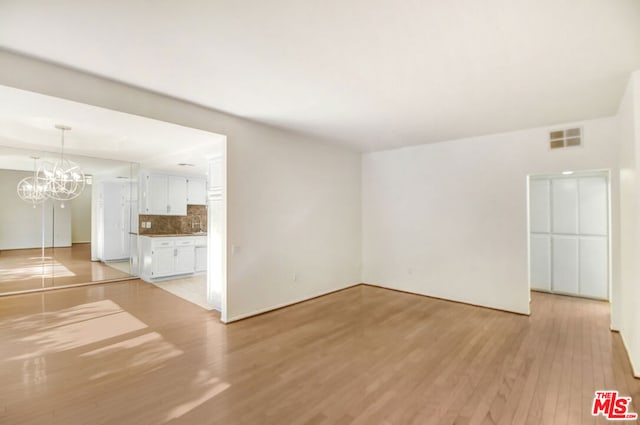 unfurnished living room with light hardwood / wood-style floors and an inviting chandelier