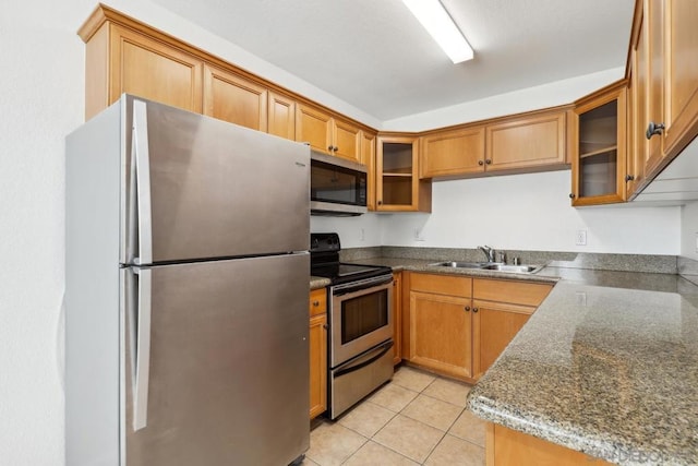 kitchen featuring sink, light tile patterned floors, stainless steel appliances, and dark stone counters