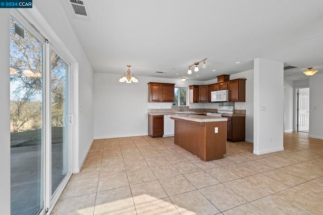 kitchen featuring sink, a kitchen island, a notable chandelier, white appliances, and light tile patterned floors