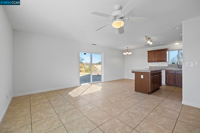 kitchen featuring light tile patterned floors, ceiling fan with notable chandelier, a center island, and sink