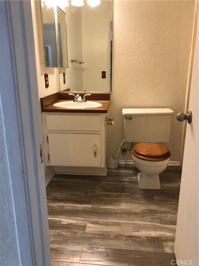 bathroom featuring vanity, wood-type flooring, and toilet