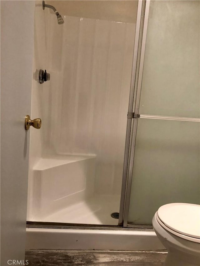 bathroom featuring toilet and an enclosed shower