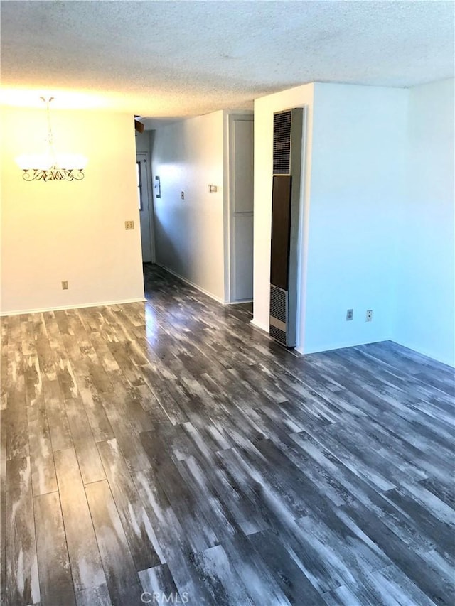 spare room featuring a textured ceiling, an inviting chandelier, and dark wood-type flooring