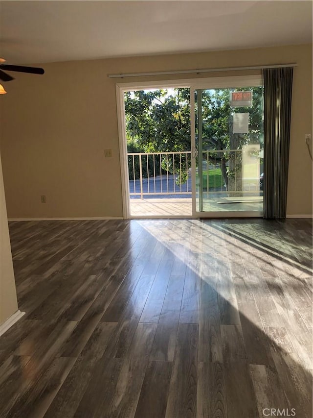 empty room with dark hardwood / wood-style floors and ceiling fan