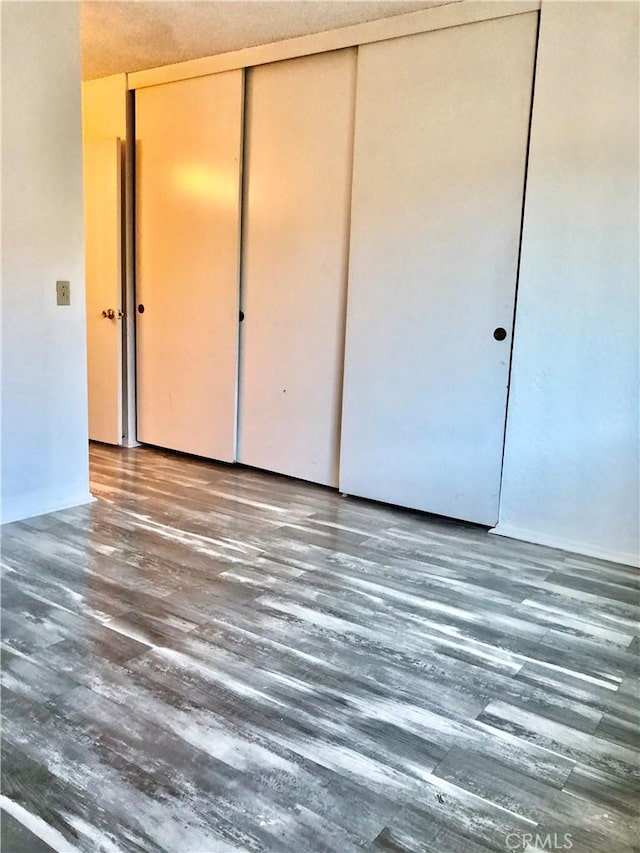 unfurnished bedroom featuring a closet and dark wood-type flooring