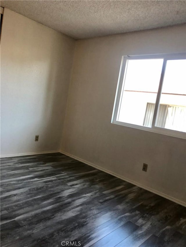 empty room with dark hardwood / wood-style flooring and a textured ceiling