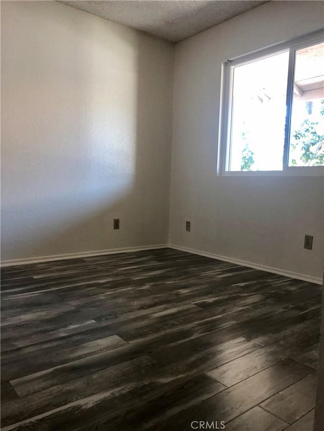 unfurnished room with dark wood-type flooring and a textured ceiling