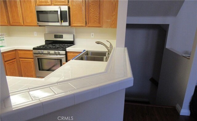 kitchen with tile countertops, appliances with stainless steel finishes, dark hardwood / wood-style floors, and sink