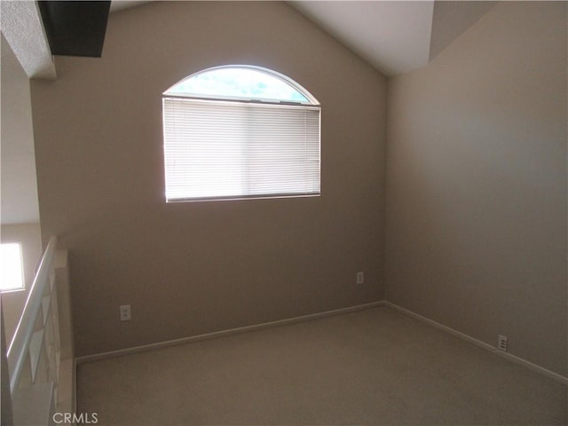 carpeted empty room featuring lofted ceiling