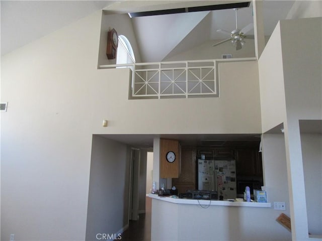 interior space featuring ceiling fan, white fridge with ice dispenser, and high vaulted ceiling