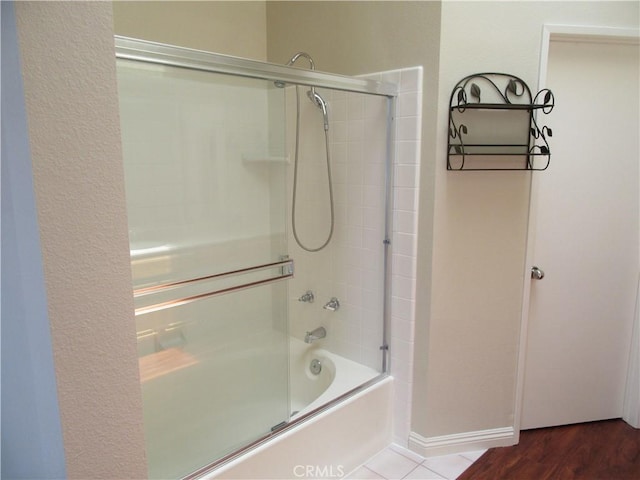 bathroom with hardwood / wood-style flooring and enclosed tub / shower combo