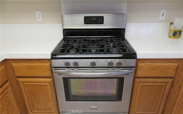 kitchen featuring tasteful backsplash, gas range, and tile counters