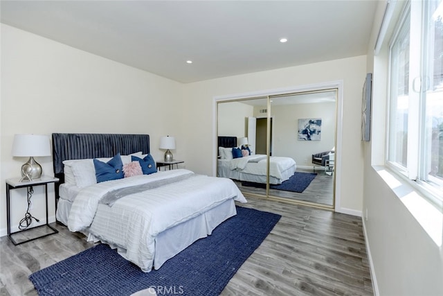 bedroom with multiple windows, a closet, and hardwood / wood-style floors