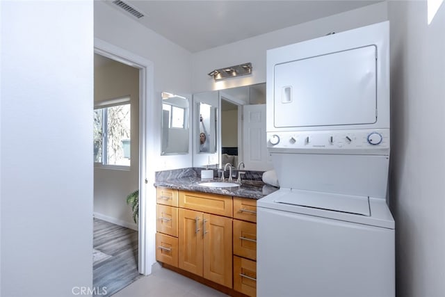 interior space with stacked washer and dryer, vanity, and hardwood / wood-style flooring