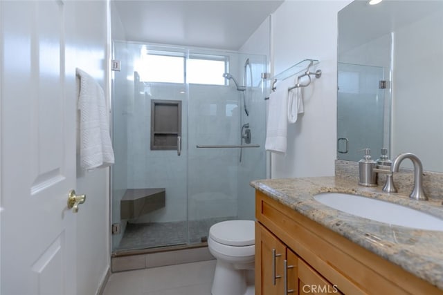 bathroom featuring tile patterned flooring, vanity, toilet, and walk in shower