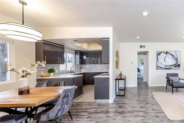 kitchen featuring decorative backsplash, sink, pendant lighting, and light wood-type flooring