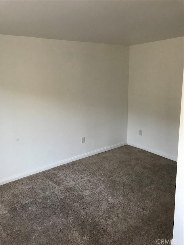 spare room with dark colored carpet