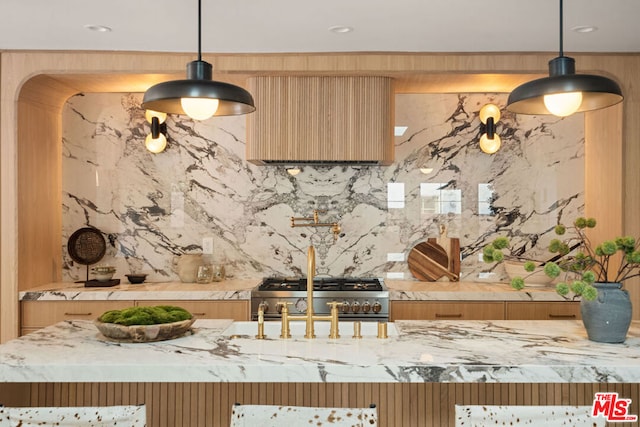 kitchen featuring tasteful backsplash, light stone countertops, stainless steel stove, and hanging light fixtures