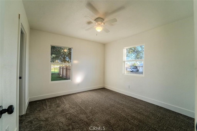 empty room with ceiling fan and dark carpet