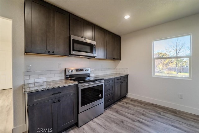 kitchen with light hardwood / wood-style floors, light stone counters, dark brown cabinetry, and appliances with stainless steel finishes