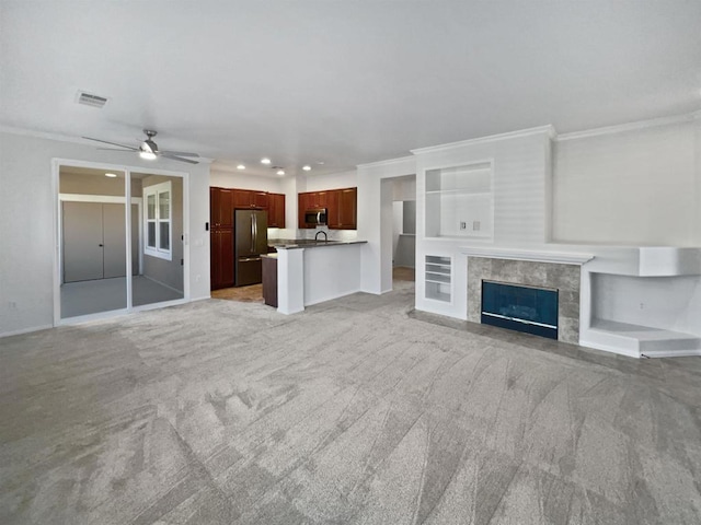 unfurnished living room with ornamental molding, a tiled fireplace, and built in shelves