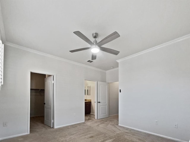 unfurnished bedroom featuring a walk in closet, connected bathroom, light carpet, a closet, and ceiling fan