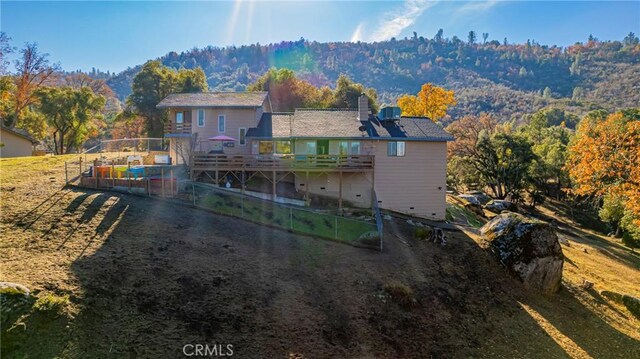 rear view of house with a deck with mountain view and a lawn