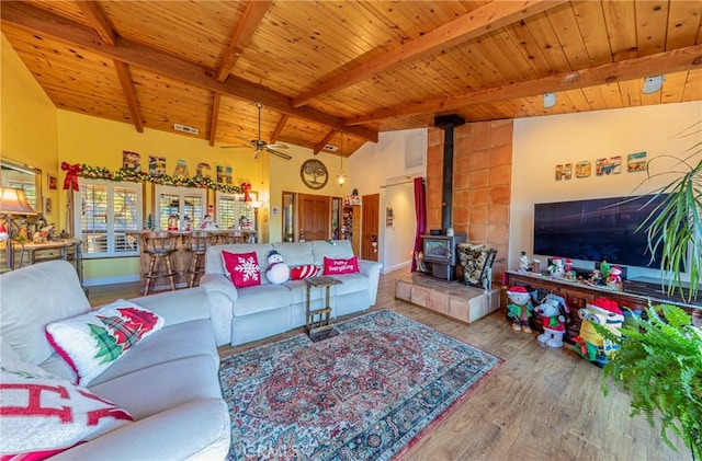 living room featuring wooden ceiling, a wood stove, hardwood / wood-style flooring, and beamed ceiling