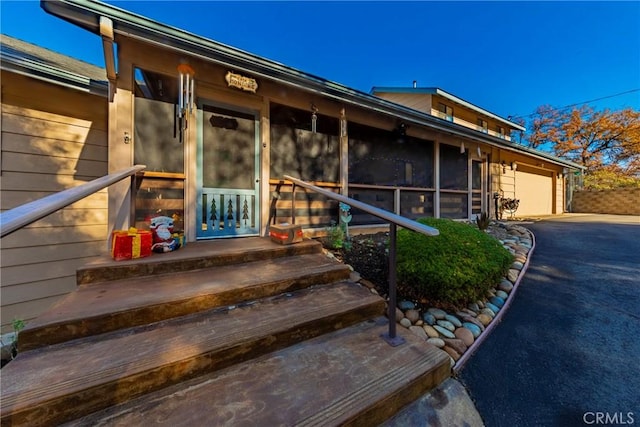 view of exterior entry with aphalt driveway and an attached garage