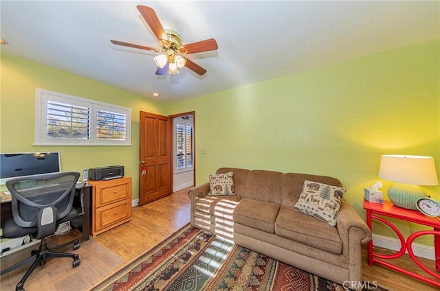 home office with a ceiling fan, light wood-type flooring, and baseboards