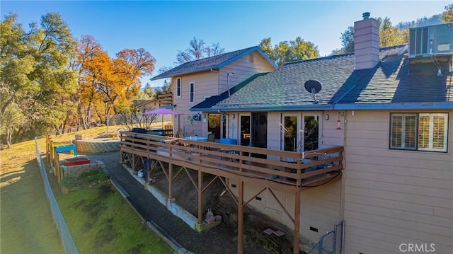 rear view of property with roof with shingles, a chimney, central AC unit, fence, and a wooden deck