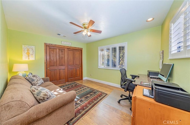 office space with visible vents, ceiling fan, light wood-style flooring, and baseboards