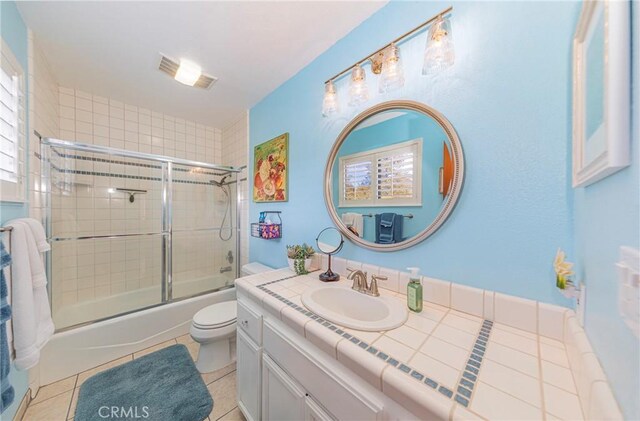 bathroom with toilet, shower / bath combination with glass door, vanity, and tile patterned floors