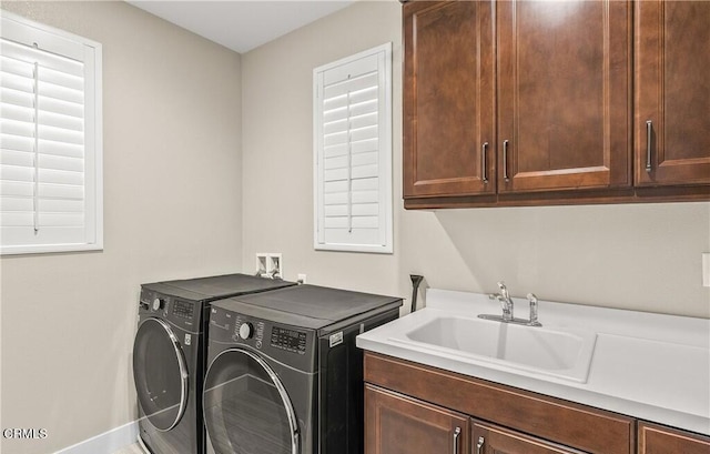 clothes washing area with washer and clothes dryer, sink, and cabinets