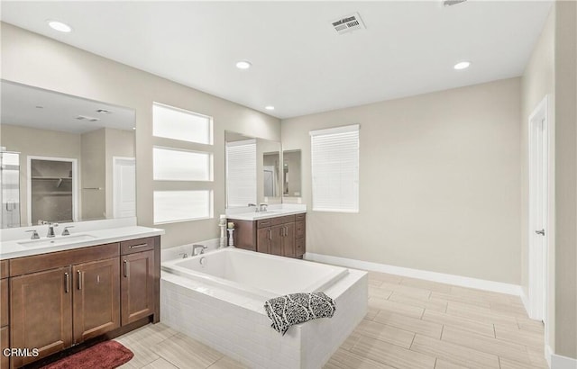 bathroom with vanity and a relaxing tiled tub