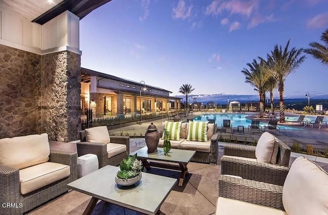 patio terrace at dusk with an outdoor living space and a community pool