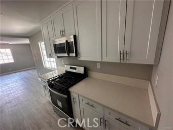 kitchen featuring white cabinets, stainless steel appliances, and light hardwood / wood-style flooring