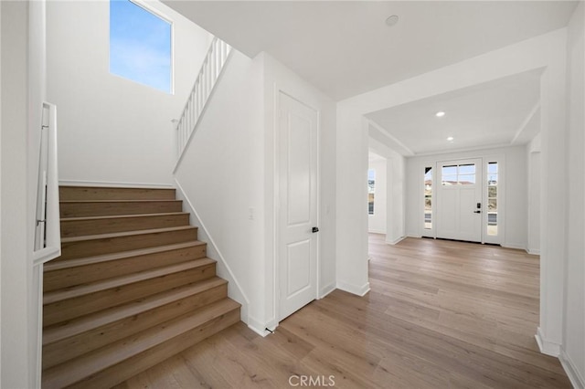 staircase featuring baseboards, wood finished floors, and recessed lighting