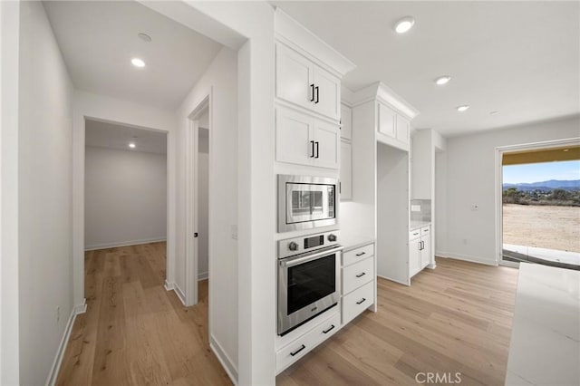 kitchen featuring baseboards, appliances with stainless steel finishes, light wood-type flooring, white cabinetry, and recessed lighting