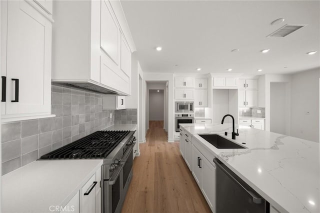 kitchen featuring visible vents, light wood-style flooring, appliances with stainless steel finishes, white cabinetry, and a sink