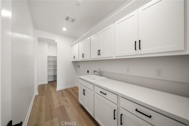 laundry area with cabinet space, light wood finished floors, visible vents, hookup for a washing machine, and a sink